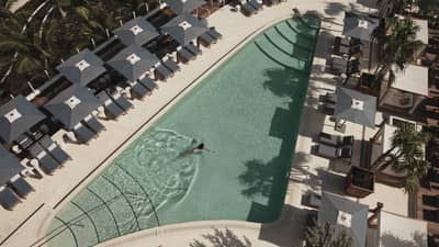 Aerial view of an outdoor pool surrounded by grey lounge chairs and umbrellas, creating a relaxing atmosphere.